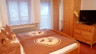 Eine Aufnahme des Doppelbetts mit Blick auf den Balkon im Appartement 1 - "Schönleiten" Schlafzimmer | © Haus Tannenblick