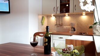 Appartement 1 - "Schönleiten" Wohnküche mit einem Glas und einer Flasche Wein am Esstisch | © Haus Tannenblick
