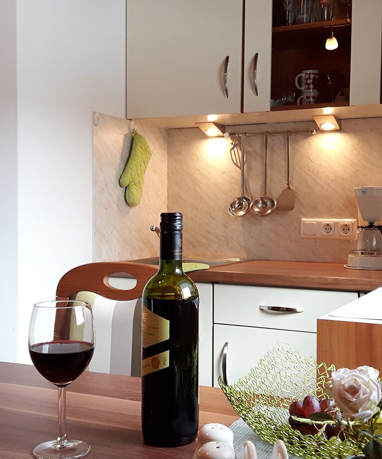 Appartement 1 - "Schönleiten" Wohnküche mit einem Glas und einer Flasche Wein am Esstisch | © Haus Tannenblick