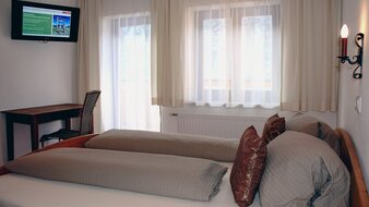 Eine Aufnahme des Doppelbetts mit Blick auf den Balkon im Appartement 1 - "Schönleiten" Schlafzimmer | © Haus Tannenblick