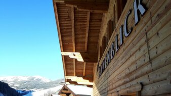 Eine Aufnahme der Hausbeschriftung des Haus Tannenblick mit winterlichem Bergpanorama im Hintergrund | © Haus Tannenblick