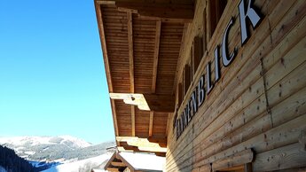 Eine Aufnahme der Hausbeschriftung des Haus Tannenblick mit winterlichem Bergpanorama im Hintergrund | © Haus Tannenblick
