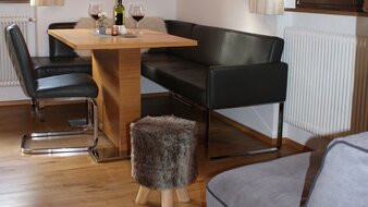 Eine Aufnahme des Esstisches mit Sitzecke und Hocker im Appartement 2 - "Reiterkogel" Wohnzimmer | © Haus Tannenblick