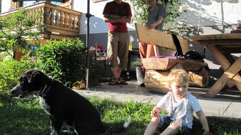 Eine Aufnahme einer Familie mit Kind und Hund im Garten von Haus Tannenblick | © Haus Tannenblick