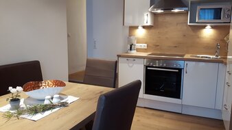 Eine Aufnahme der voll ausgestattete Wohnküche mit Esstisch im Appartement 3 - "Kohlmais" | © Haus Tannenblick