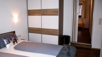 Ein Blick auf das Doppelbett und Kleiderschrank in einem der Schlafzimmer von Appartement 3 - "Kohlmais" | © Haus Tannenblick