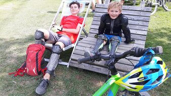 Eine Aufnahme von Kindern in Mountainbike Montur auf Liegen rastend | © Haus Tannenblick