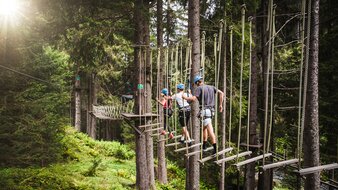 Eine Gruppe balanciert entlang einer Hängebrücke im Hochseilpark in Saalbach Hinterglemm | © saalbach.com - Mia Knoll