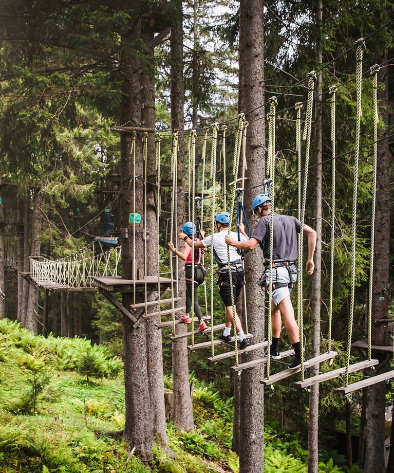 Eine Gruppe balanciert entlang einer Hängebrücke im Hochseilpark in Saalbach Hinterglemm | © saalbach.com - Mia Knoll