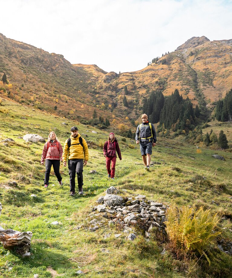Eine Gruppe bei einer Herbstwanderung entlang eines Feldwegs am Berg | © saalbach.com - Karin Pasterer