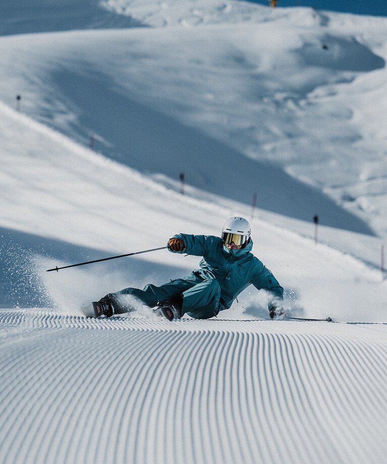 Ein Skifahrer lehnt sich weit in seinen Schwung auf einer frisch präparierten Piste | © saalbach.com - Georg Lindacher